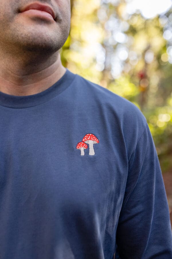 A man wearing a blue shirt with red mushrooms on it.